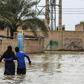 An Iranian family walks through a flooded street in a village around the city of Ahvaz