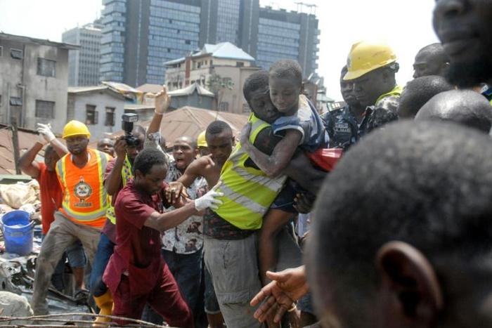 Survivor: Emergency workers pluck a child from the collapsed building. The disaster left 20 dead, according to a new toll