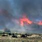 Men believed to be Islamic State fighters walk amidst flames and smoke in the jihadist group's last remaining position in the village of Baghouz in eastern Syria on March 18, 2019