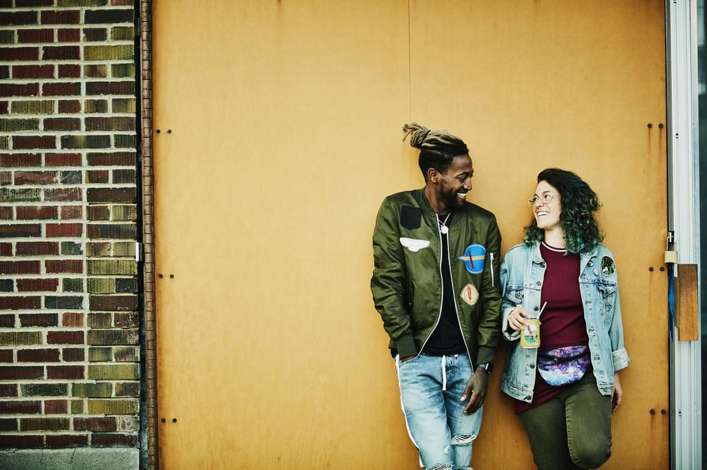 Portrait of smiling friends standing in front of yellow wall