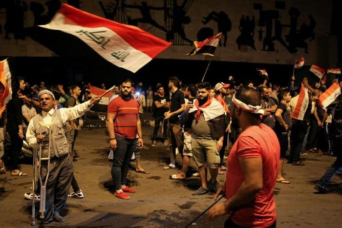 Iraqi protesters wave the national flag as they take part in anti-government demonstrations in central Baghdad's Tahrir Square