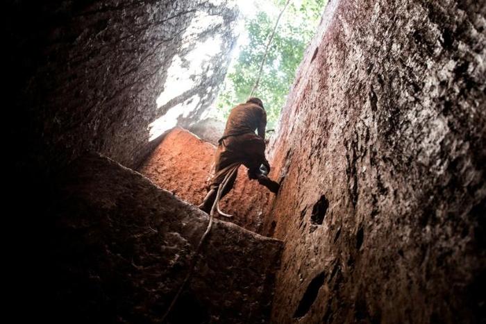 A subsistence miner in Mabakulu, eastern DR Congo, clambers out of a mine shaft with the help of a vine. Safety in Congo's illegal mining sector is poor, and accidents are frequent (file picture)