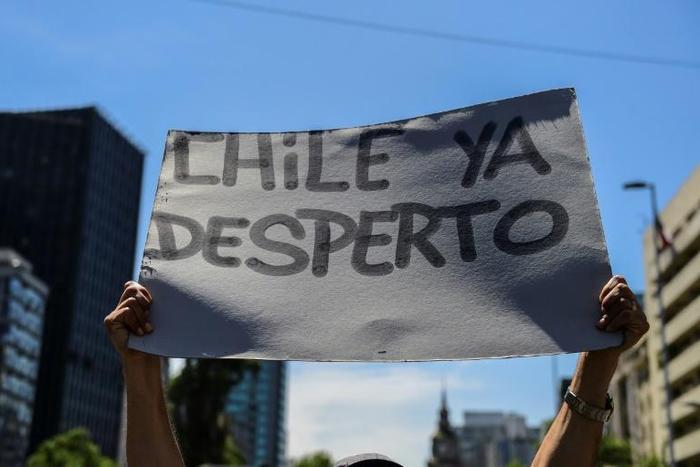 A demonstrator in Santiago holds a sign reading "Chile has awakened"