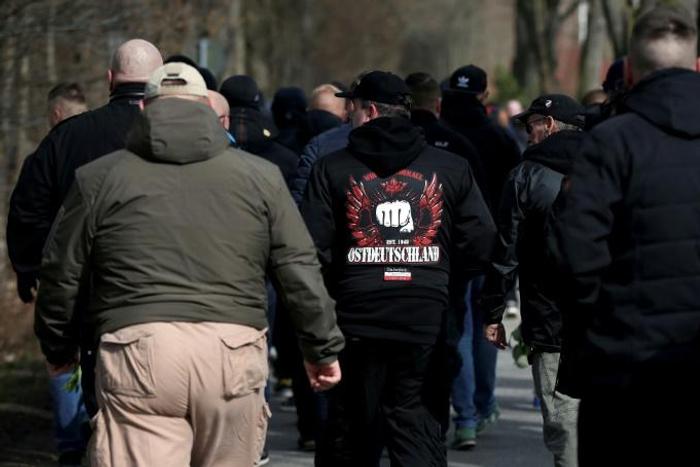 The silent, mostly male crowd lined the road leading to a cemetery for the funeral of Thomas Haller, the co-founder of a group called "HooNaRa" (Hooligans-Nazis-Racists)