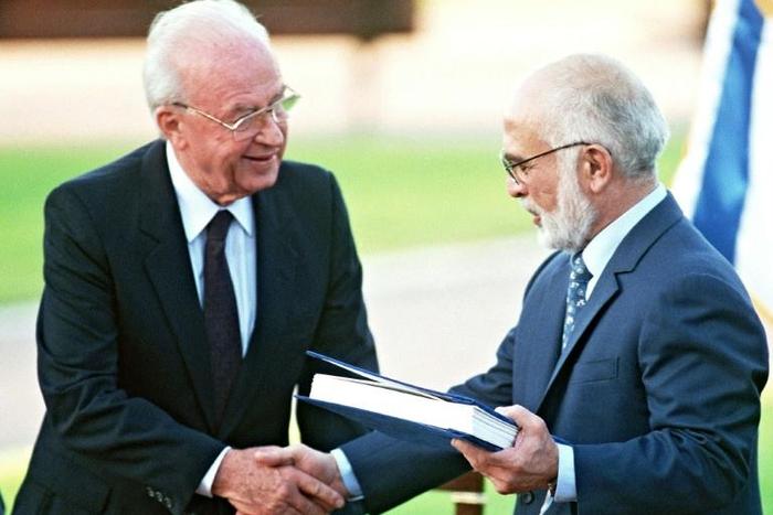 Jordan's King Hussein (R) and Israeli Premier Yitzhak Rabin shake hands after exchanging the documents of the peace treaty on the southern shore of the Sea of Galilee