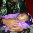 The baby was plucked from debris inside a house where his mother and siblings were found dead