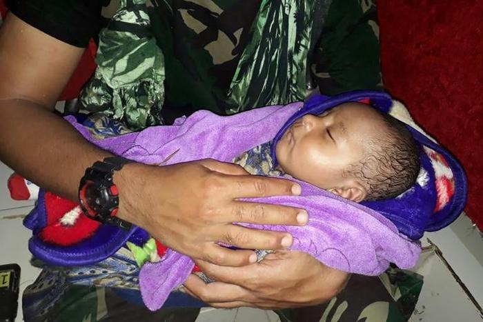 The baby was plucked from debris inside a house where his mother and siblings were found dead