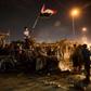 An Iraqi protester waves the national flag as he stands atop a burnt out police vehicle outside the local government headquarters in the southern city of Basra on Friday