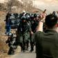 A Palestinian protester makes an insulting gesture to Israeli border guards during a protest against construction of an Israeli outpost near an Israeli settlement in the occupied West Bank