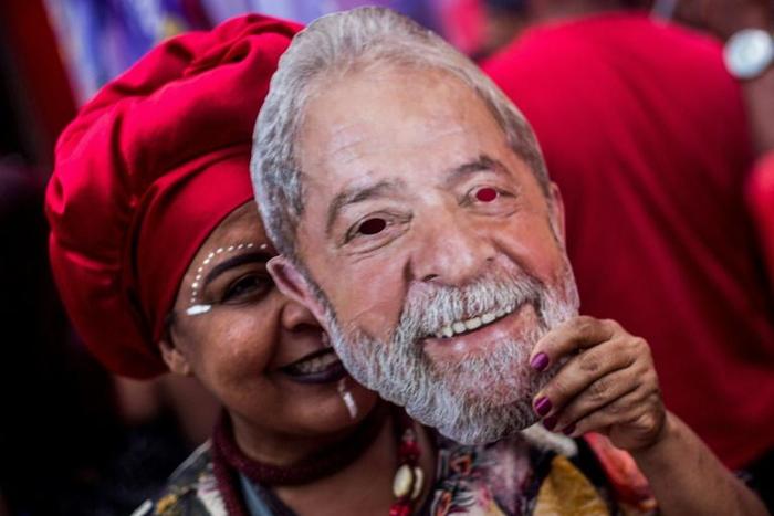 A supporter of Brazil's Workers Party holds a mask with the face of imprisoned former Brazilian president Luiz Inacio Lula da Silva