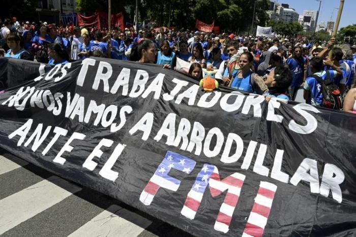 Demonstrators hold a banner reading "We, the workers, will not kneel before the IMF," during a protest February 13, 2019
