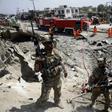 Afghan security forces walk as municipal workers clean up from an attack in Kabul