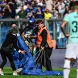 Security staff evacuate a parachutist who landed on the pitch at Sassuolo's stadium in Reggio-Emilia during a game against Inter Milan