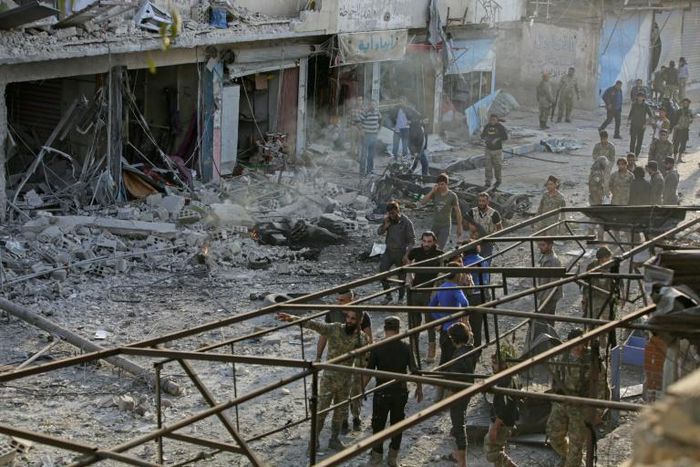 Turkey-backed Syrian fighters inspect the site of a car bomb explosion in the northern Syrian town of Tal Abyad, on the border with Turkey, on Saturday
