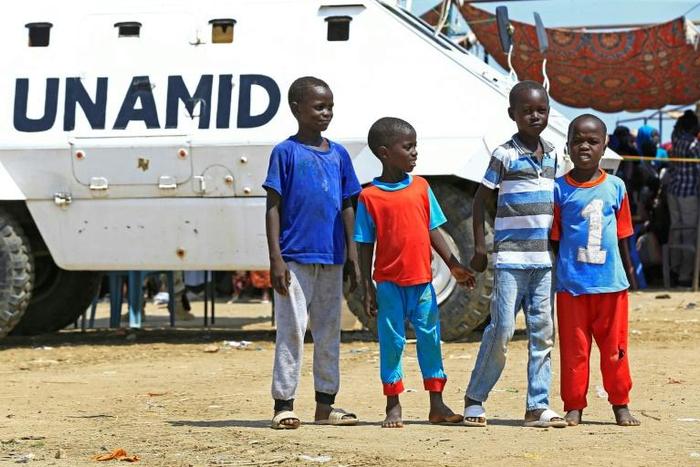 Displaced Sudanese boys pose for a picture in front of a UN-African Union mission to Darfur (UNAMID) vehicle at the Kalma camp for internally displaced people in Darfur's state capital Niyala on October 9, 2019