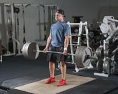 Full length of young man lifting barbell in gym