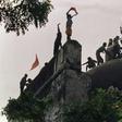 Hindu fundamentalists shout and wave banners as they stand on the top of a stone wall and celebrate the destruction of the 16th century Babri Mosque in Ayodhya in 1992