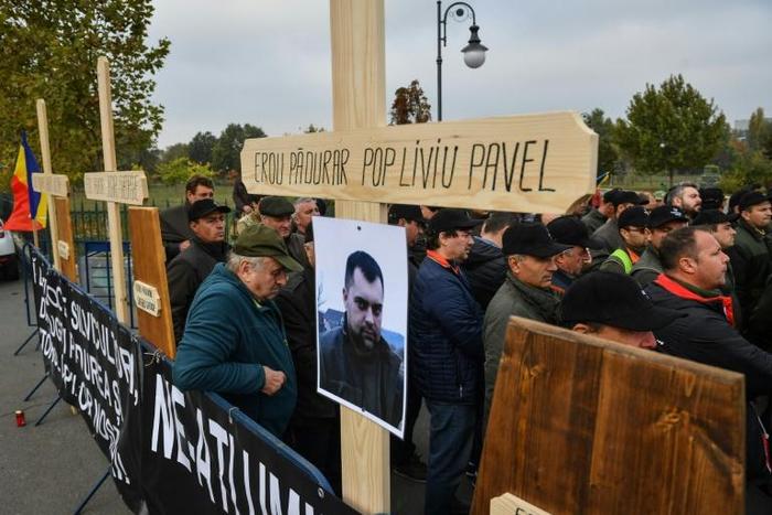 Forest guards stand next to wooden crosses bearing the names of their killed colleagues during a protest near the Romanian Parliament building in Bucharest