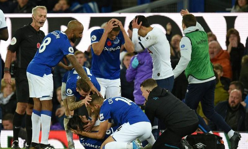 Everton players comfort teammate André Gomes (on the floor) after suffering a serious injury against Tottenham