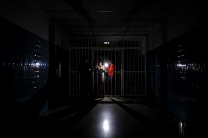 People stand on a dark corridor at Miguel Perez Carreno hospital, in Caracas, during the worst power outage in Venezuela's history