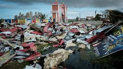 People collect metal sheets from a damaged supermarket to rebuild their houses destroyed by Cyclone Idai in Beira, Mozambique