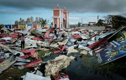 People collect metal sheets from a damaged supermarket to rebuild their houses destroyed by Cyclone Idai in Beira, Mozambique