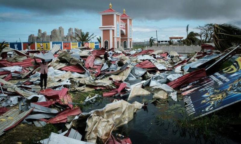 People collect metal sheets from a damaged supermarket to rebuild their houses destroyed by Cyclone Idai in Beira, Mozambique