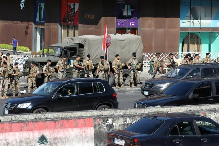 Lebanese soldiers get the traffic flowing again after removing protesters' roadblocks as the government's resignation under pressure from the streets looks set to ease a two-week-old lockdown
