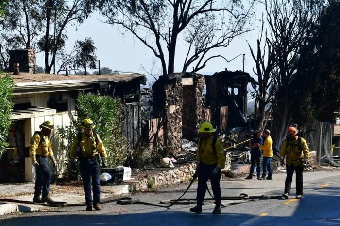 Firefighters gather their hoses near destroyed homes along North Tigertail Road near the Getty Center in Los Angeles on October 29