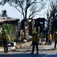 Firefighters gather their hoses near destroyed homes along North Tigertail Road near the Getty Center in Los Angeles on October 29