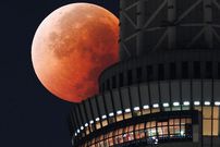 The moon appears from behind the Tokyo Skytree during the total lunar eclipse above the Japanese capital. [JIJI Press/AFP]