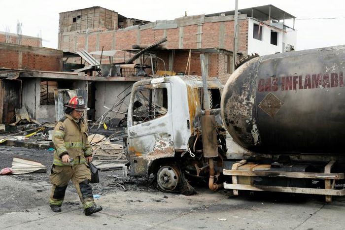 A fireman walks past the tanker truck that exploded in a Lima neighborhood on January 23, 2020, killing several people and igniting houses and cars