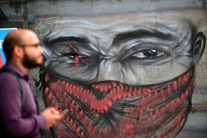 A man walks by graffiti depicting a demonstrator with an injured eye, in clear reference to those hurt in recent clashes, on November 18