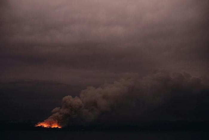 This handout photo taken on January 6, 2020 and received on January 7 from the Australian Department of Defence shows a fire in the distance seen from the Royal Australian Navy's HMAS Adelaide ship off the coast in Eden in New South Wales