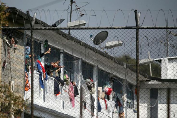 Inmates extend their hands at the Modelo prison in Bogota after a riot on March 22 left 23 prisoners dead and 90 wounded