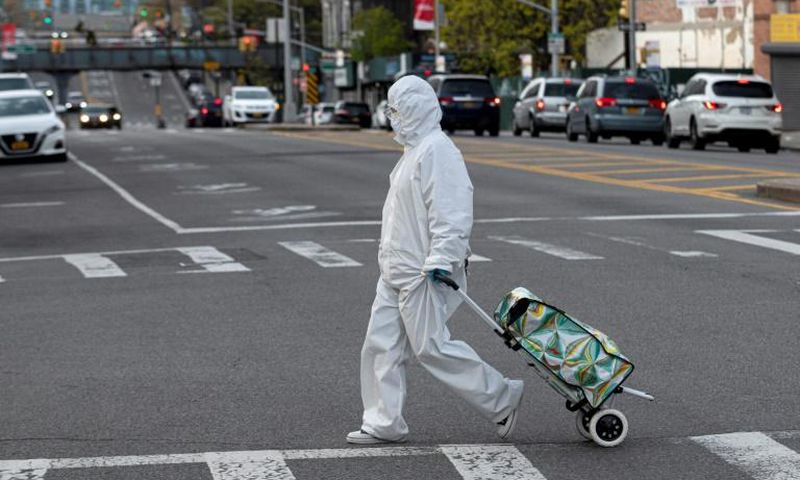 A woman wearing a hazmat suit and googles pulls her grocery cart through New York City on April 20, 2020