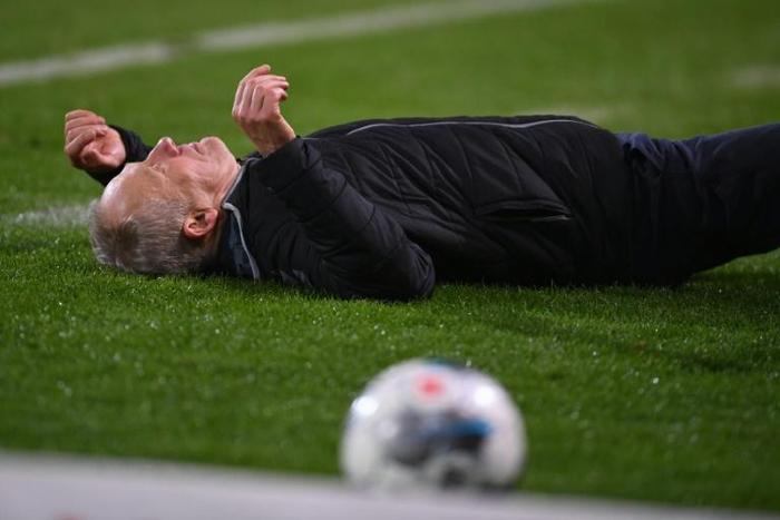 Freiburg head coach Christian Streich lies on the pitch after being barged by Frankfurt captain David Abraham on Sunday.