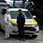 A policeman talks to a member of the Spanish Army's Military Emergency Unit (UME) wearing a protective suit outside the Palacio de Hielo shopping mall where an ice rink was turned into a temporary morgue on March 24, 2020 in Madrid