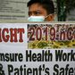 A health worker wearing a face mask holds a placard during a protest in front of a government hospital in Manila