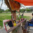 A barber wearing a facemask cuts a customer's hair at an open-air stall in Islamabad