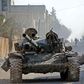 Turkey-backed Syrian fighters ride a tank in the town of Saraqib in the eastern part of the Idlib province in northwestern Syria