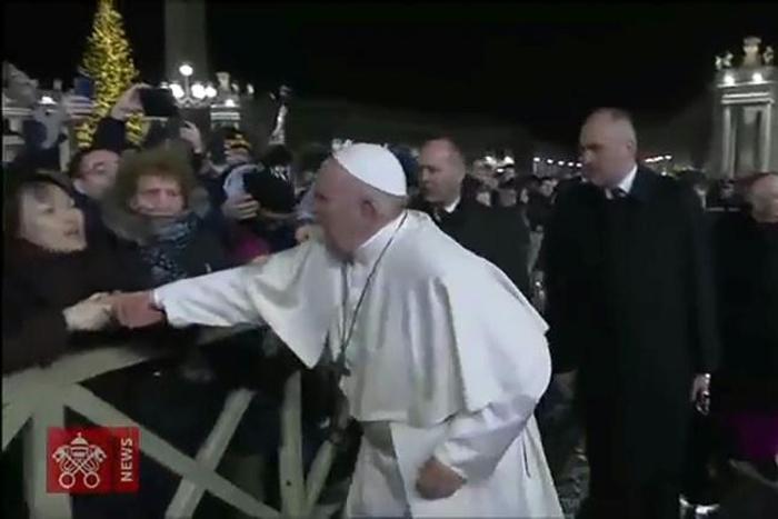 A frame grab taken from a handout video made available by Vatican Media on January 1, 2020 shows a lady (L) grabbing at Pope Francis's hands as he greets Catholic faithful as he arrives to celebrate New Year's Eve mass in Vatican City