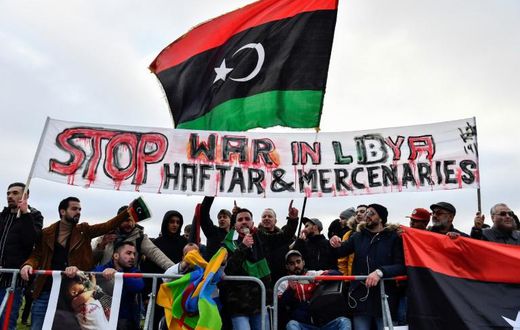 Protesters hold a banner reading "Stop war in Libya, Haftar and mercenaries" during a protest near the chancellery during the Peace summit on Libya at the Chancellery in Berlin on January 19, 2020