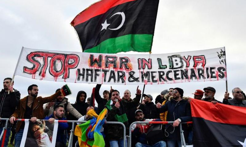 Protesters hold a banner reading "Stop war in Libya, Haftar and mercenaries" during a protest near the chancellery during the Peace summit on Libya at the Chancellery in Berlin on January 19, 2020