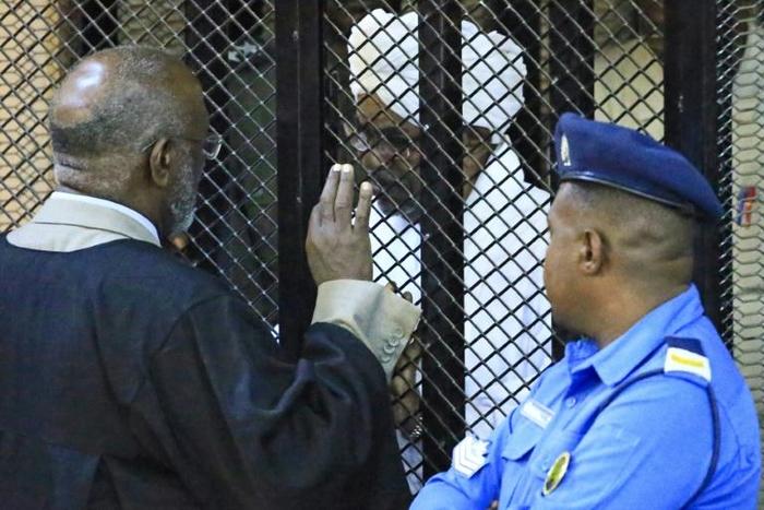 Sudan's deposed president Omar al-Bashir sits in a defendant's cage during his corruption trial in Khartoum on December 14
