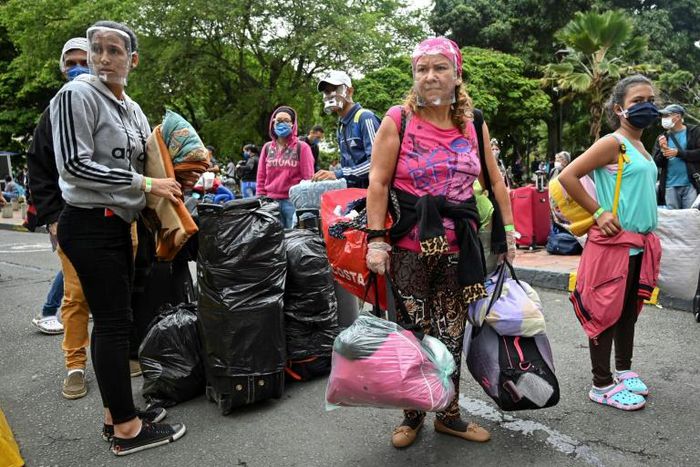 Venezuelan migrants loaded down with their belongins board a bus to go home, this time fleeing the new coronavirus