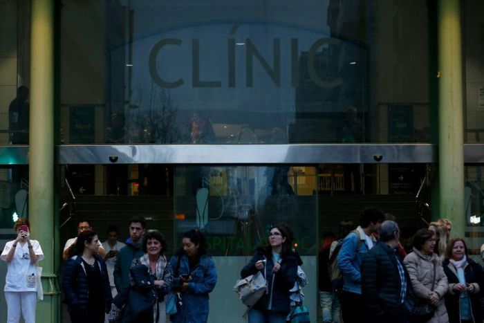 People walk outside the Hospital Clinic in Barcelona on February 25, 2020 where a woman was hospitalised in a suspected case of coronavirus