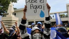 A student carries a sign reading "Let the water pass" during a protest of students and relatives of political prisoners, in Managua on Tuesday
