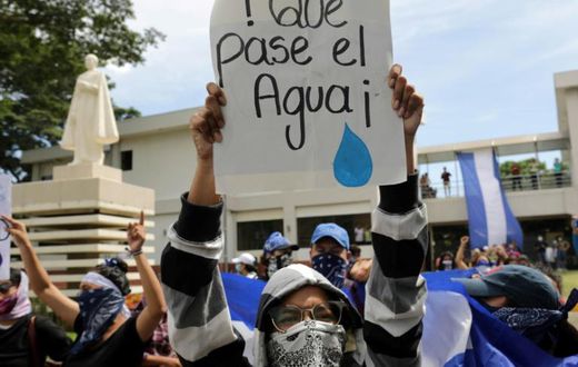 A student carries a sign reading "Let the water pass" during a protest of students and relatives of political prisoners, in Managua on Tuesday