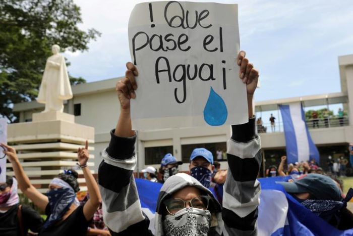 A student carries a sign reading "Let the water pass" during a protest of students and relatives of political prisoners, in Managua on Tuesday